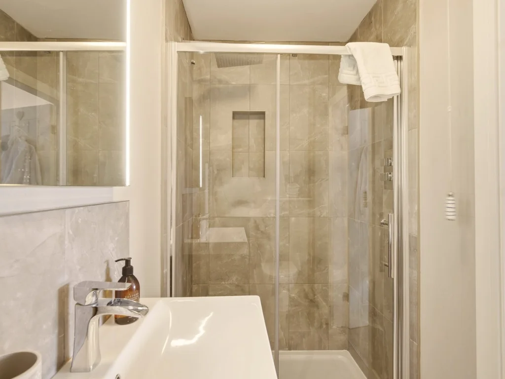 Walk-in shower with recessed shelf, illuminated mirror and vanity basin