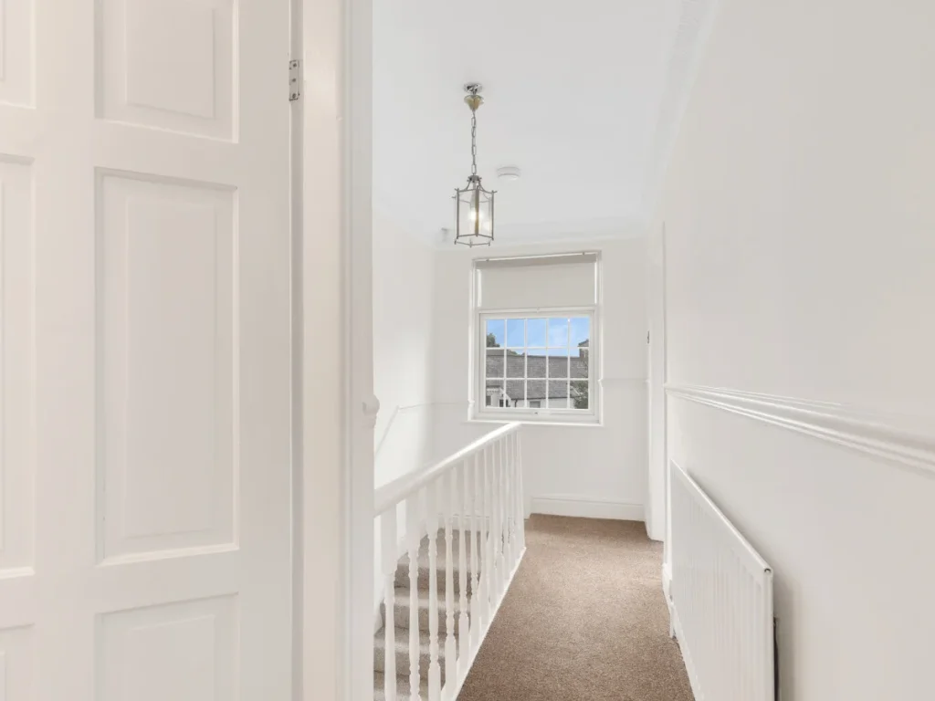 Bright first-floor landing with white bannister and natural window light