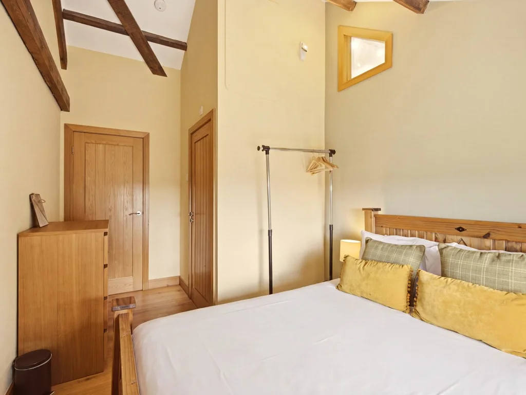 King-size bedroom with exposed beams and warm timber furnishings