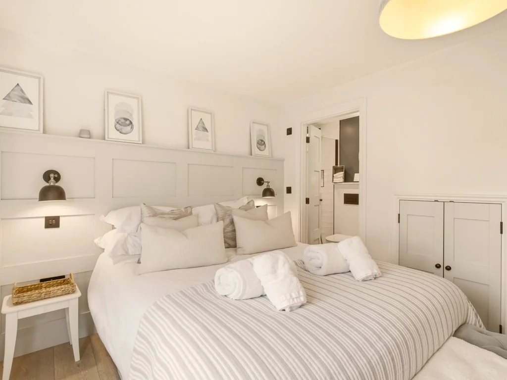 King bedroom with panelled headboard, integrated bedside lighting and en-suite