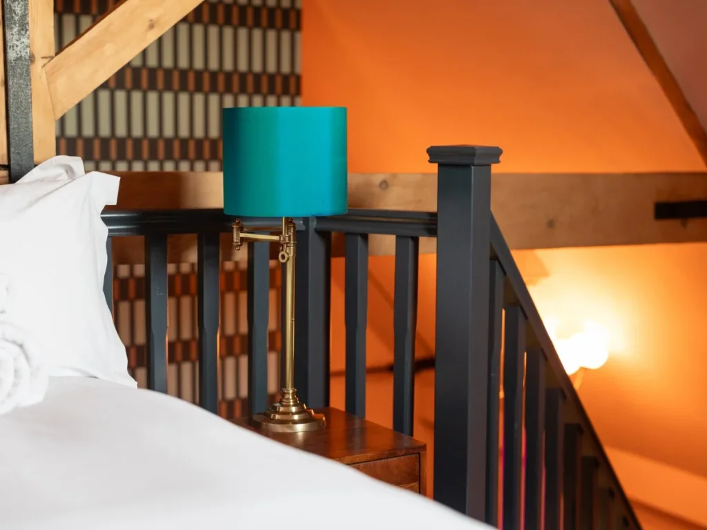 1.74Bedside view with exposed beams, patterned wall and warm lighting