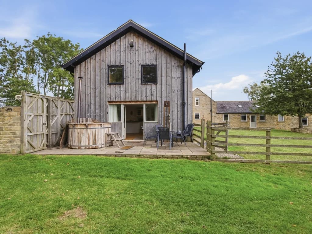 Rear exterior of Drum Barn with patio, hot tub and open lawn