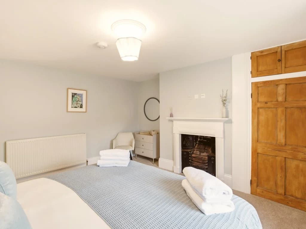 Bright King bedroom with decorative fireplace and period features.