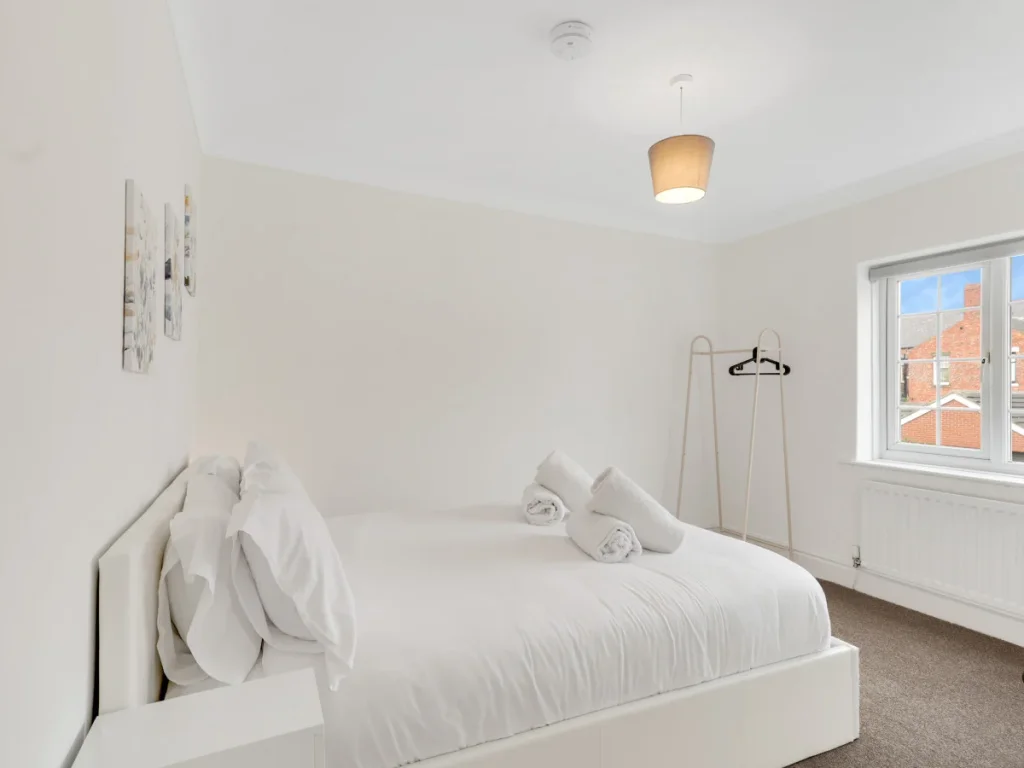 King bedroom with large window, hanging rail and plenty of natural light