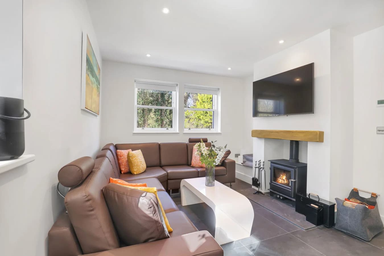 Living area with corner sofa, log burner and wall-mounted TV