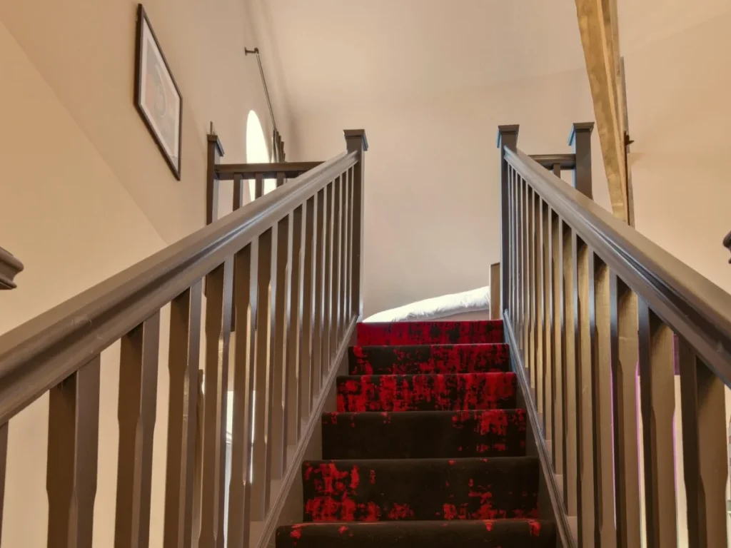 Carpeted staircase with dark timber railings leading to the mezzanine