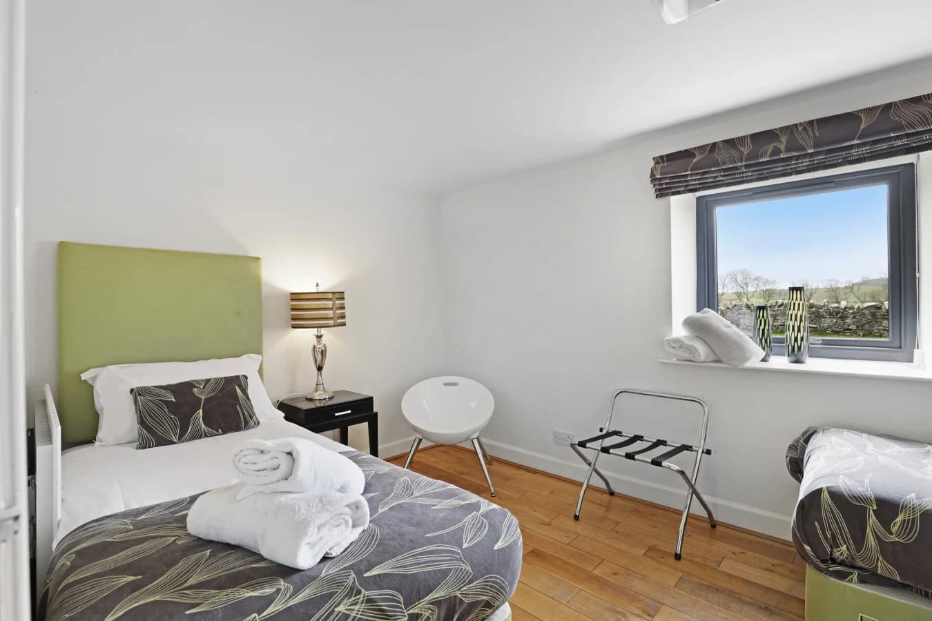 Twin bedroom with green headboards and countryside views