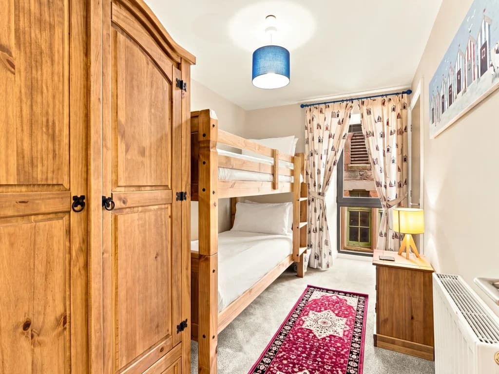 Bunk bedroom with wardrobe, bedside table and full-size bunk beds.