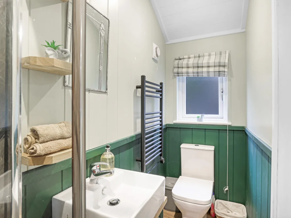 Compact bathroom with green panelling, shower, and modern fittings.