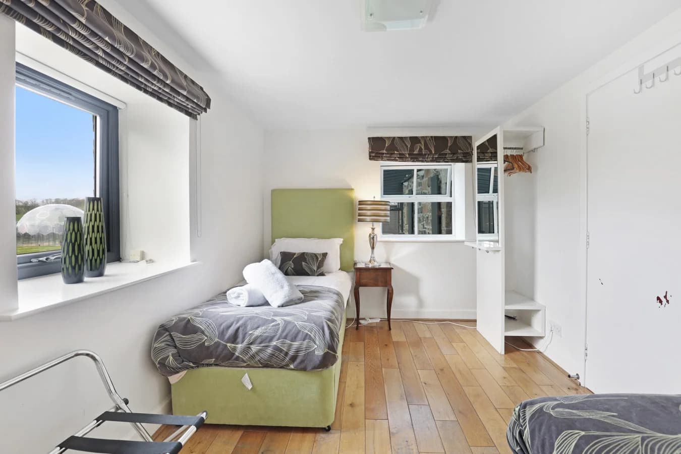 Twin bedroom with green headboards and oak flooring