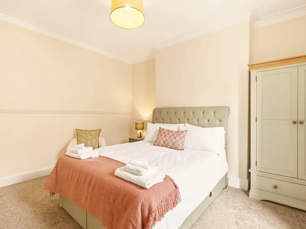 King bedroom with upholstered headboard and freestanding wardrobe.