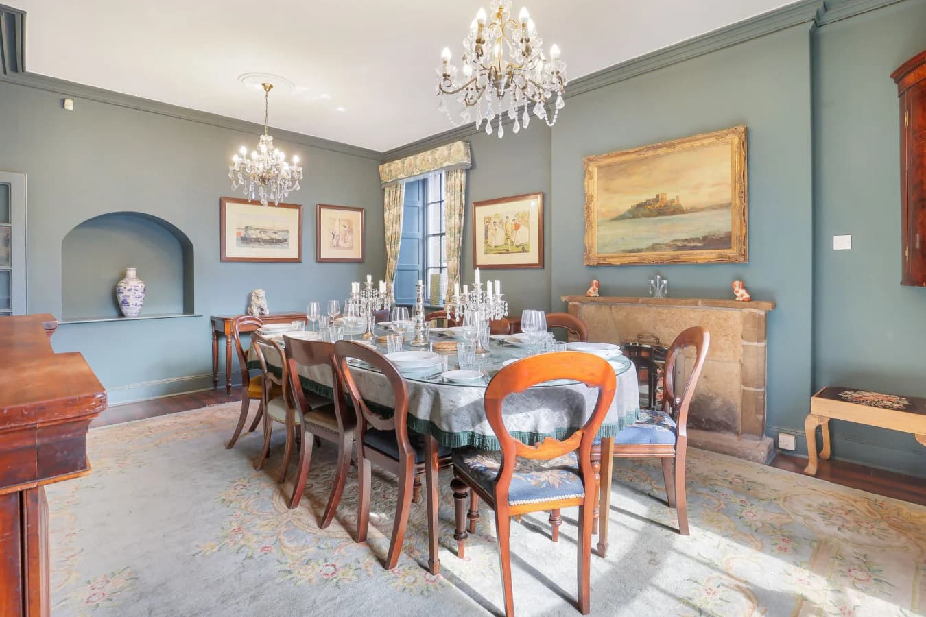 Formal dining room with teal walls, chandelier and antique furnishings