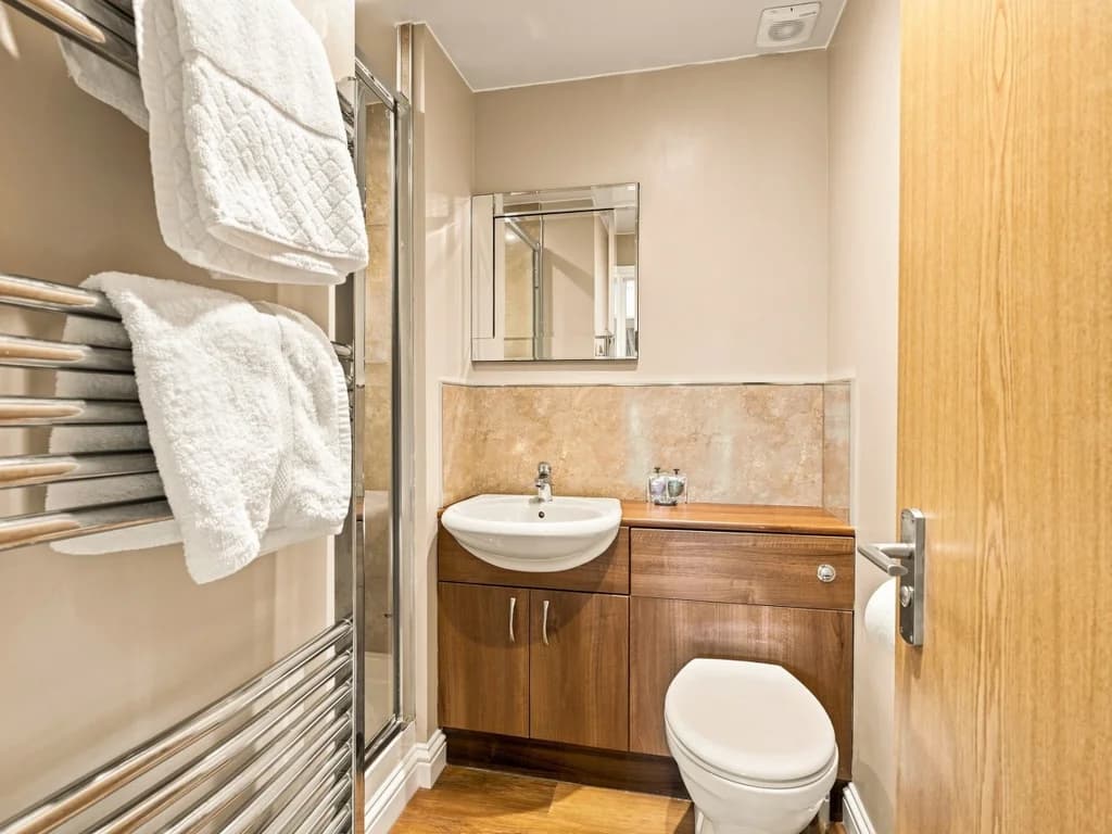 En-suite shower room with vanity unit, heated towel rail and mirror.