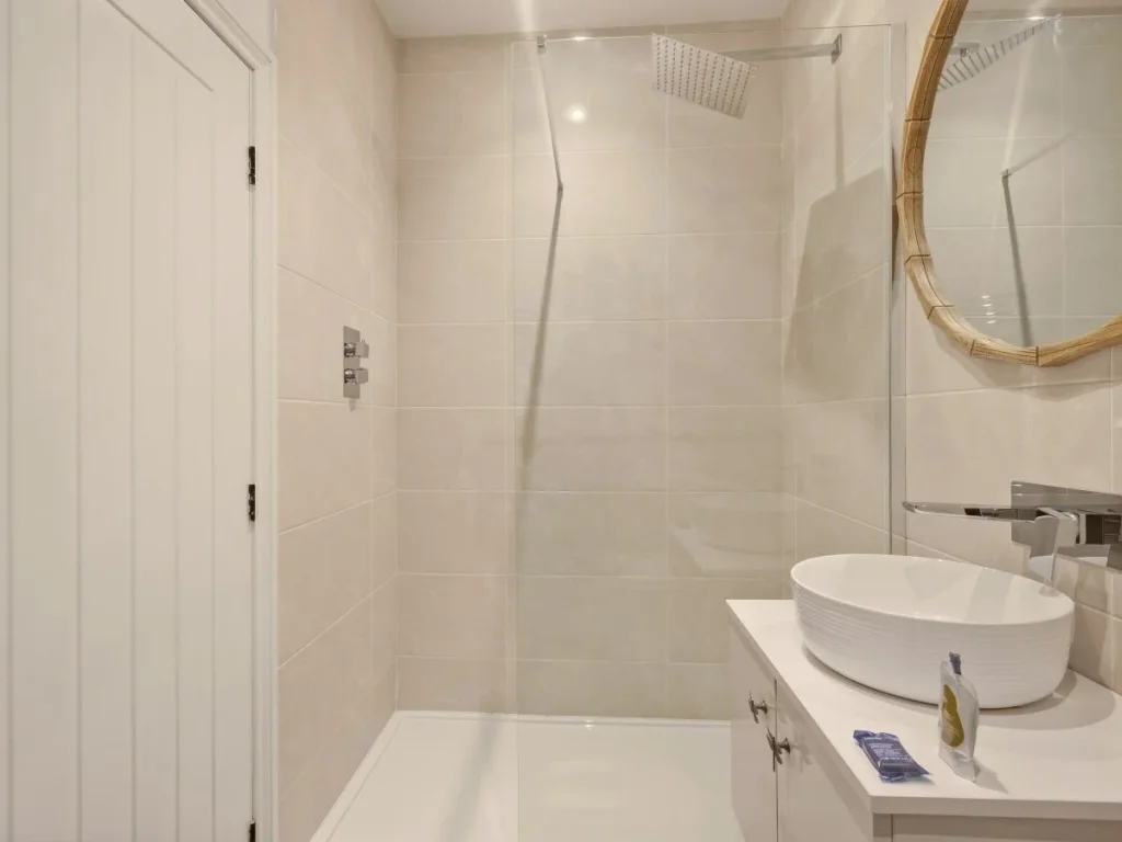 Walk-in rainfall shower with glass screen and contemporary fittings.