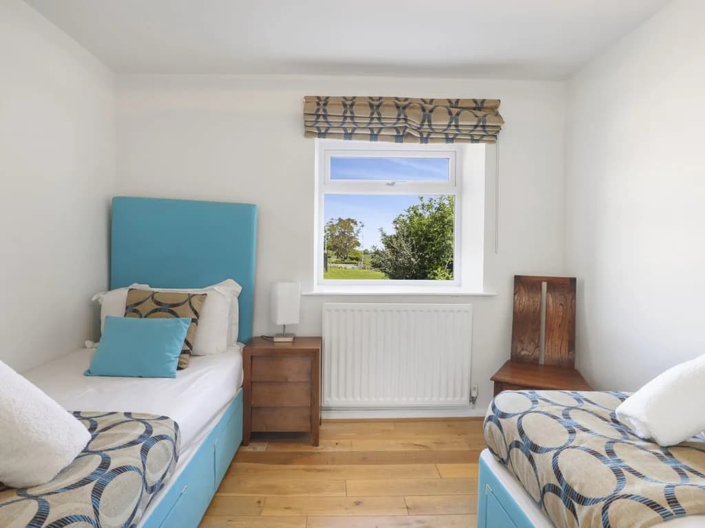 Twin bedroom with matching bedside table and garden-facing window