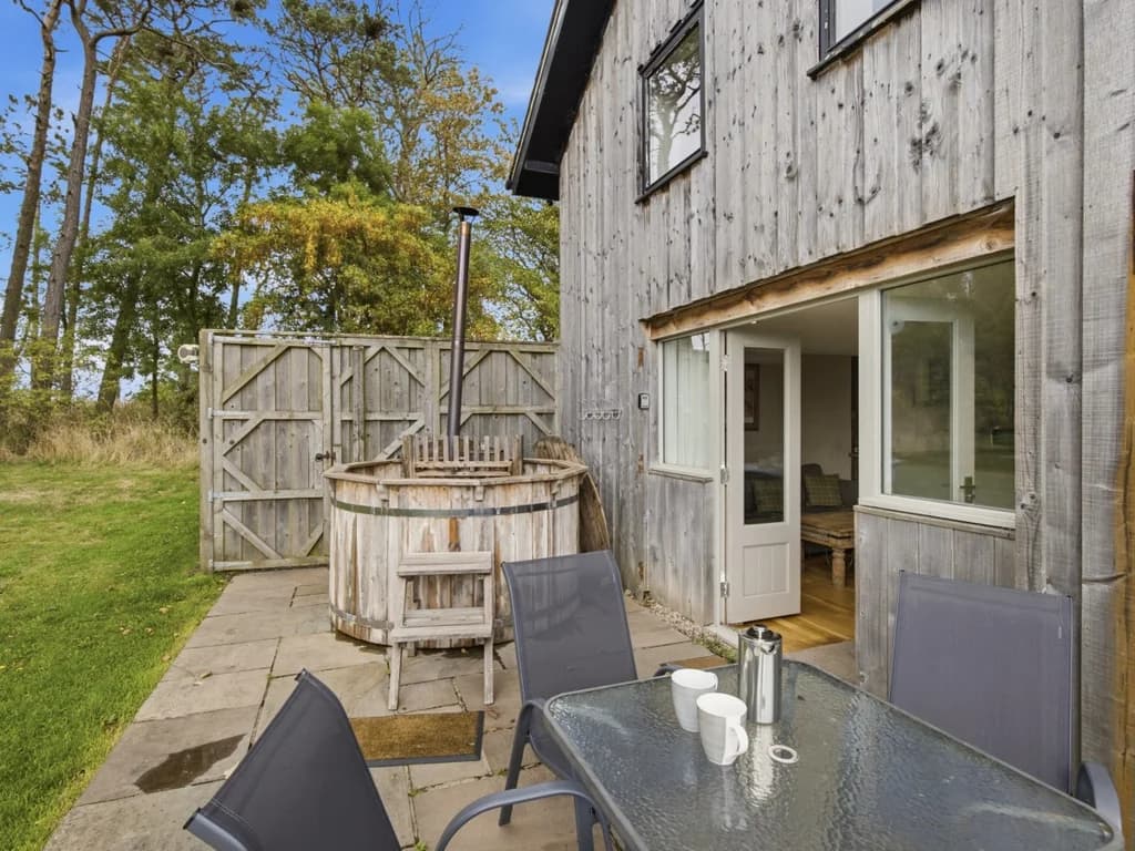 Patio dining area with wood-fired hot tub beside Drum Barn