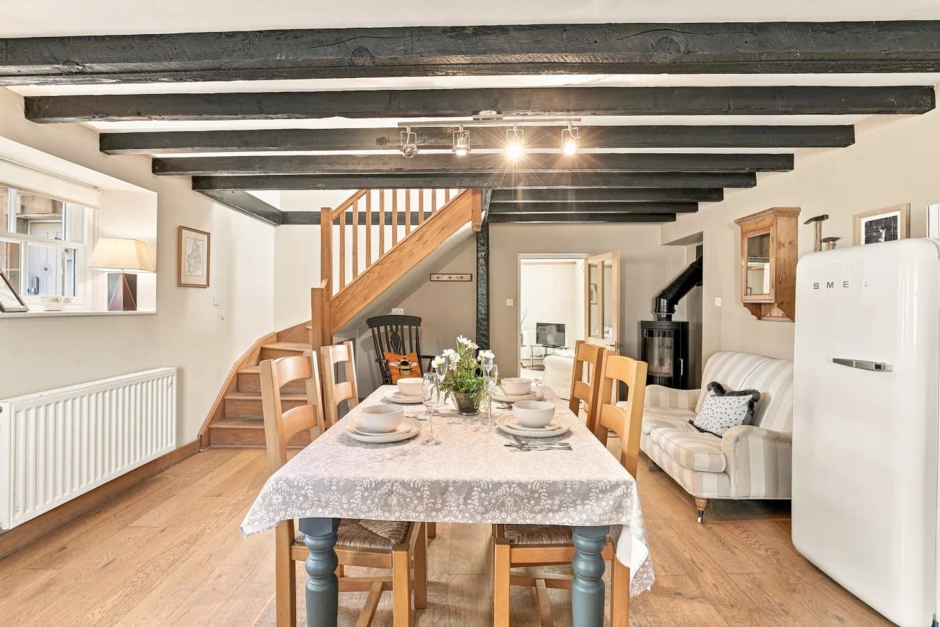 Dining area with exposed beams, wooden staircase and table setting