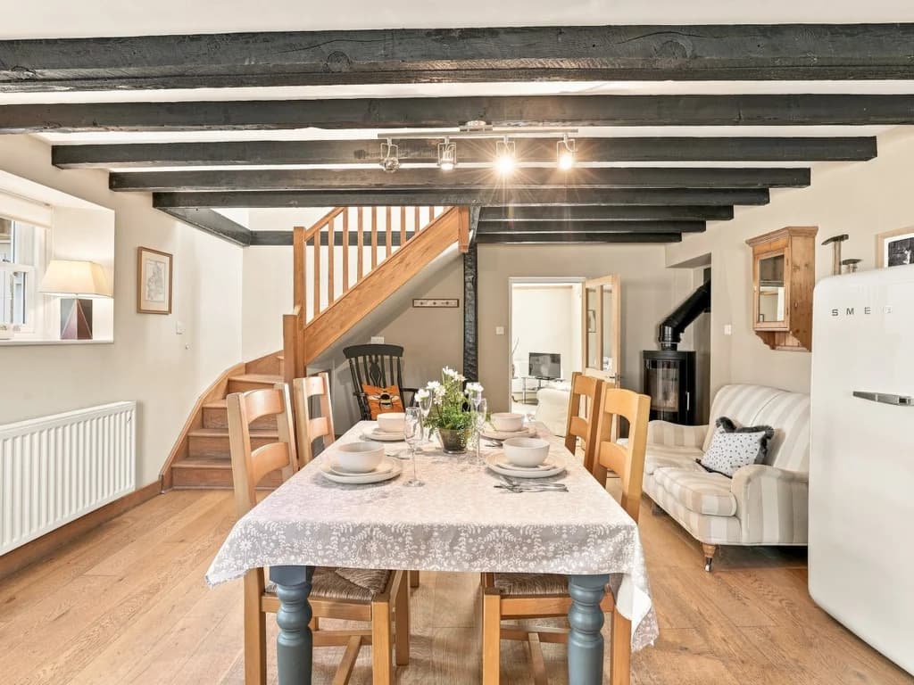 Dining area with exposed beams, wooden staircase and table setting