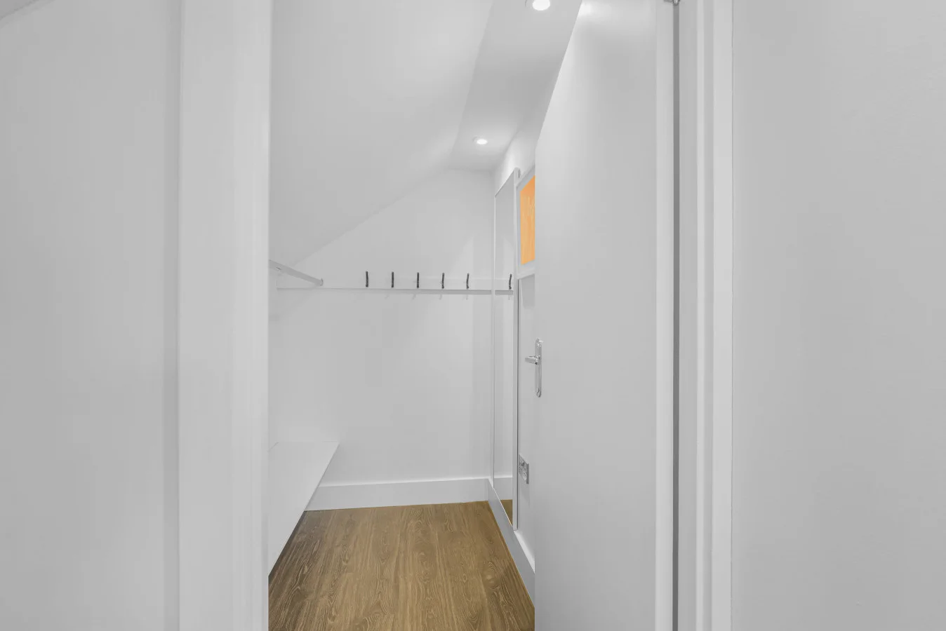 Walk-in wardrobe with hanging space and oak flooring