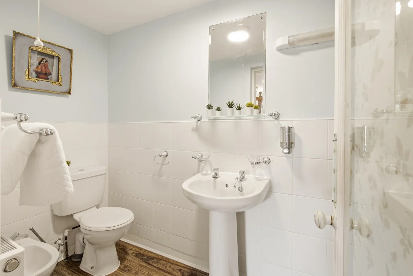 White bathroom with pedestal sink, WC and walk-in shower.