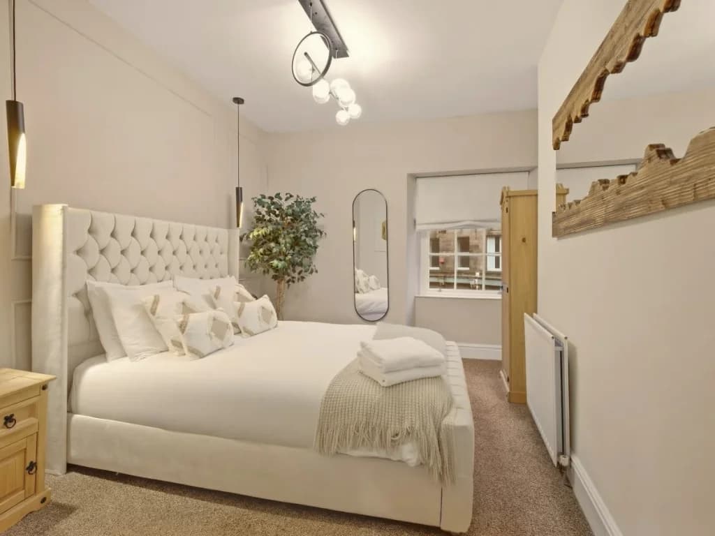 Second-floor king bedroom with full-length mirror and wooden wardrobe.