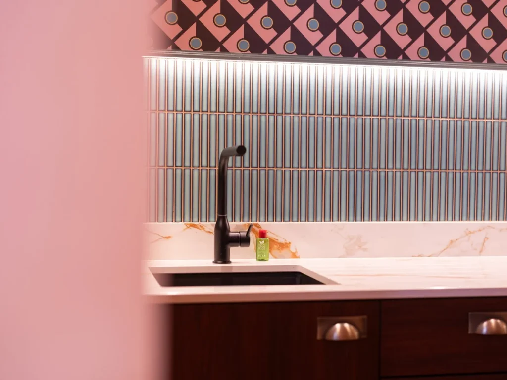 Close-up of the kitchenette sink, tiled splashback and modern fittings.