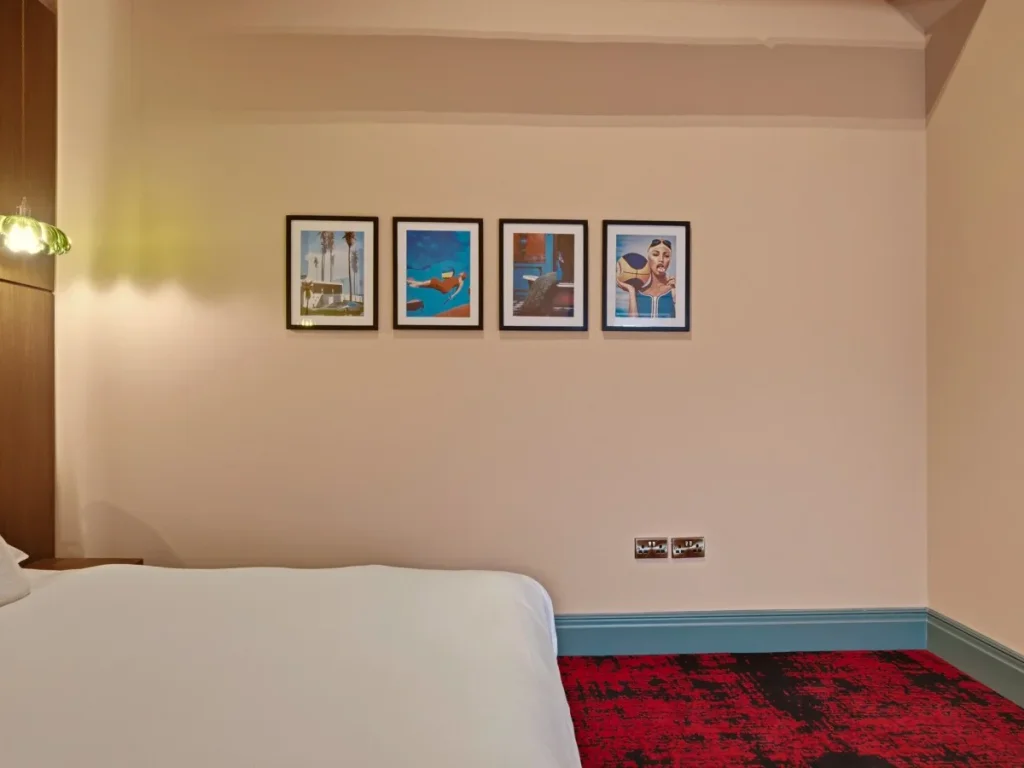 Double bedroom with colourful framed artwork and red patterned carpet