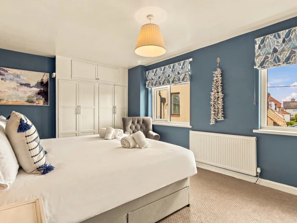 King bedroom with twin windows, fitted wardrobes and dressing table.