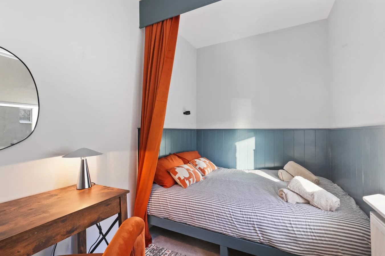 Snug sleeping area with blue panelling, warm textiles and natural light