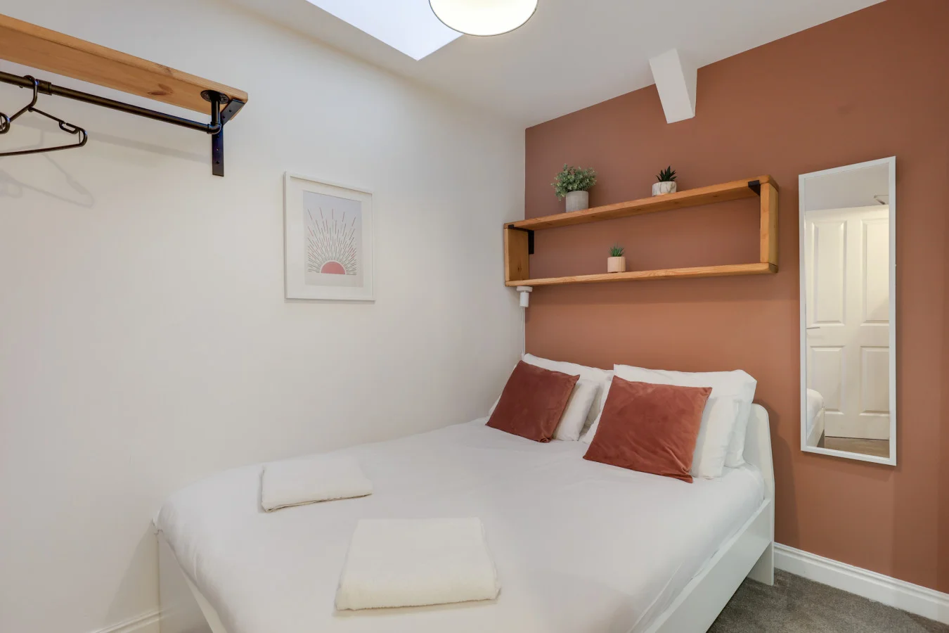 Cosy double bedroom with terracotta feature wall and skylight
