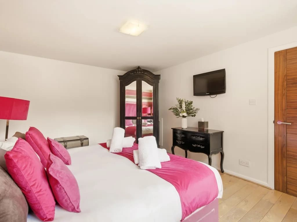 Bedroom with super-king bed, TV, wardrobe and courtyard views.
