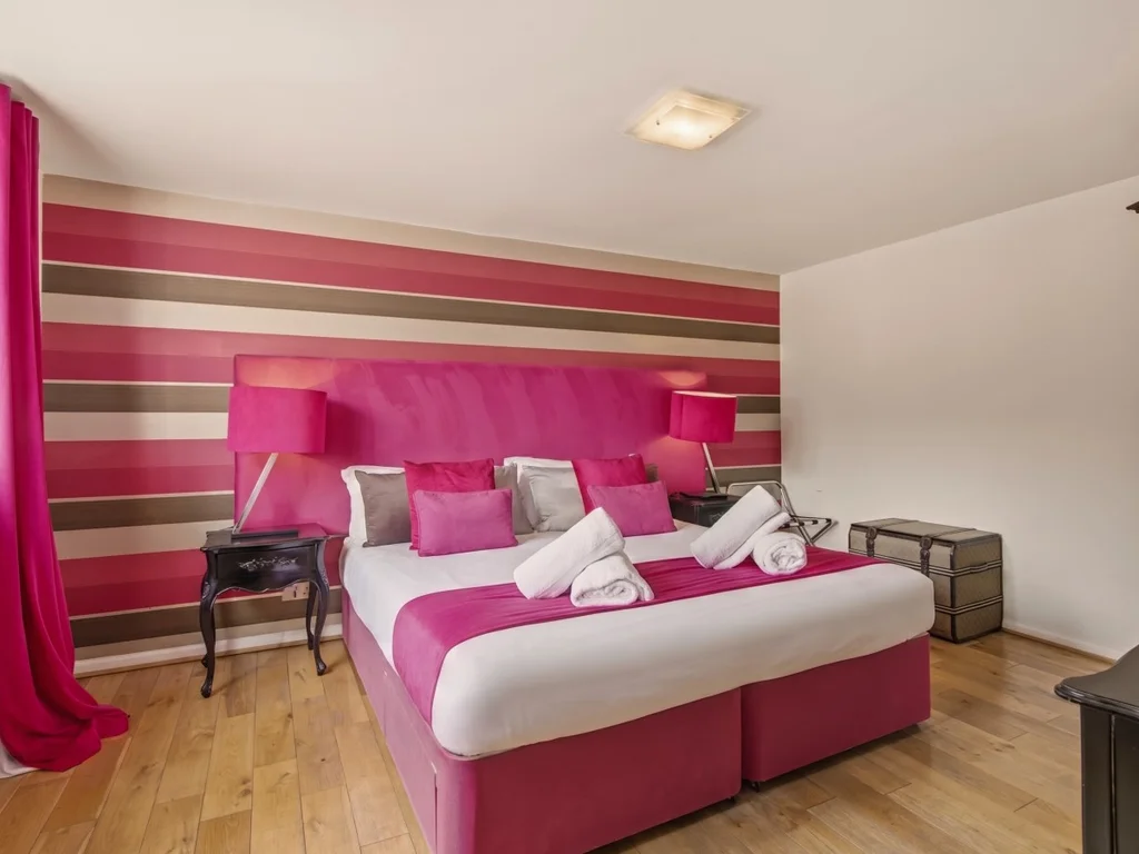 Super-king bed with bold striped feature wall and hardwood flooring