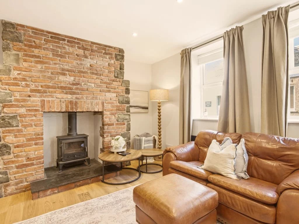Exposed brick fireplace with wood-burning stove and leather seating.