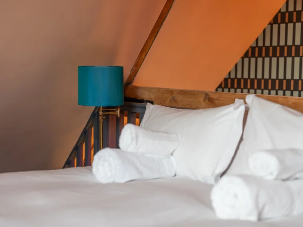 Mezzanine double bed with teal bedside lamp and fresh towels