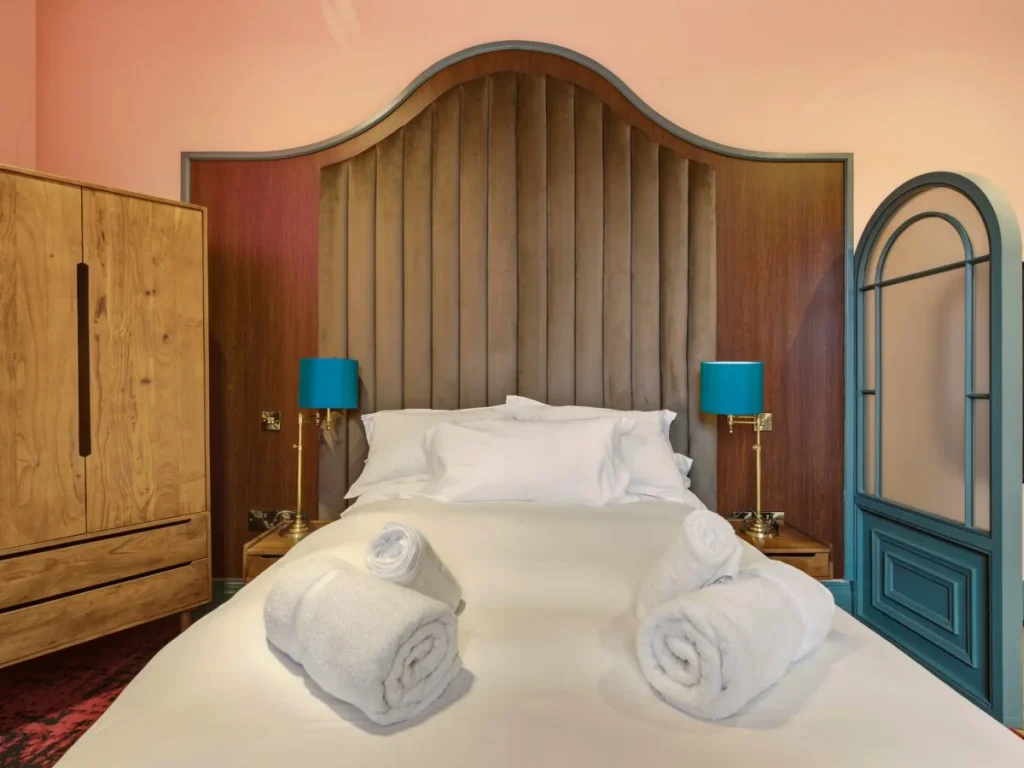Double bed framed by statement wood panelling with bedside lighting.