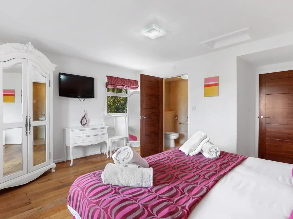 Bright bedroom with wall-mounted TV and white furniture