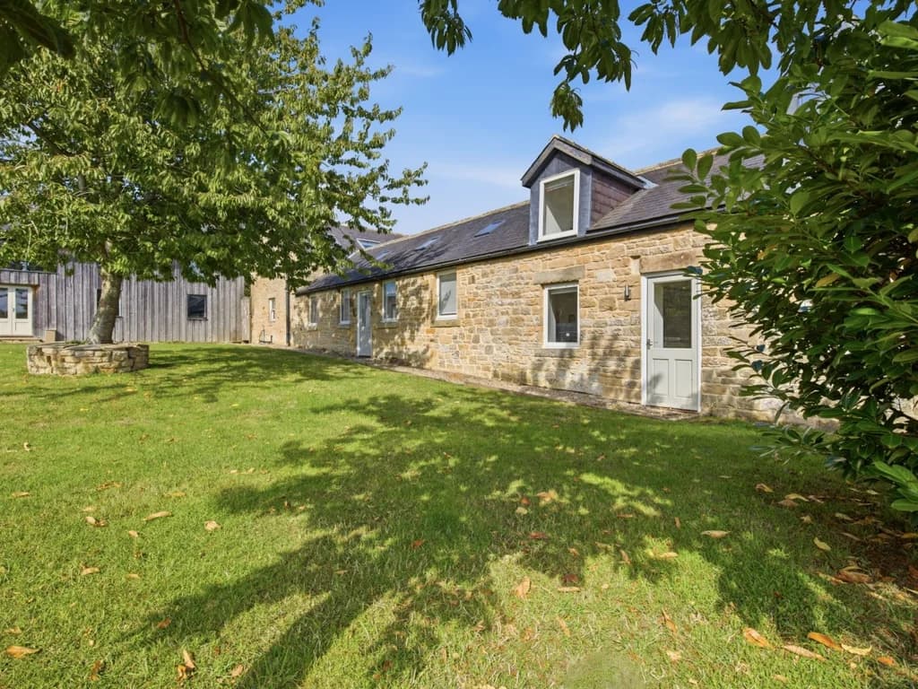 Hayloft Cottage stone exterior framed by lawn and mature trees