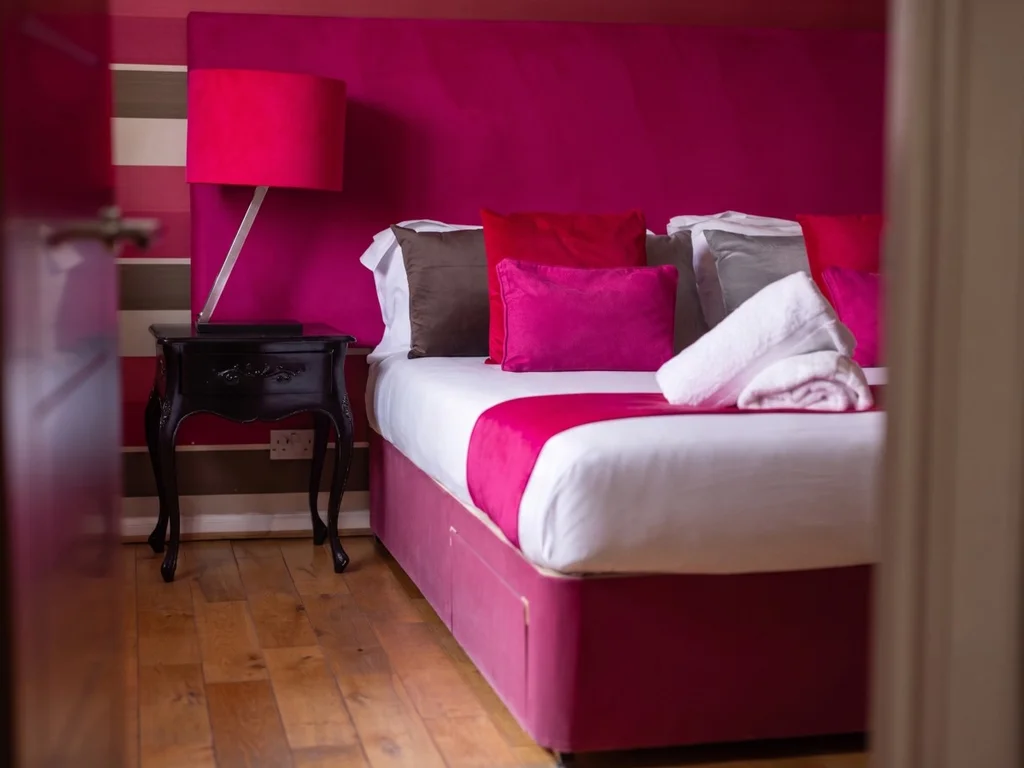 Super-king bedroom with magenta headboard and black bedside table