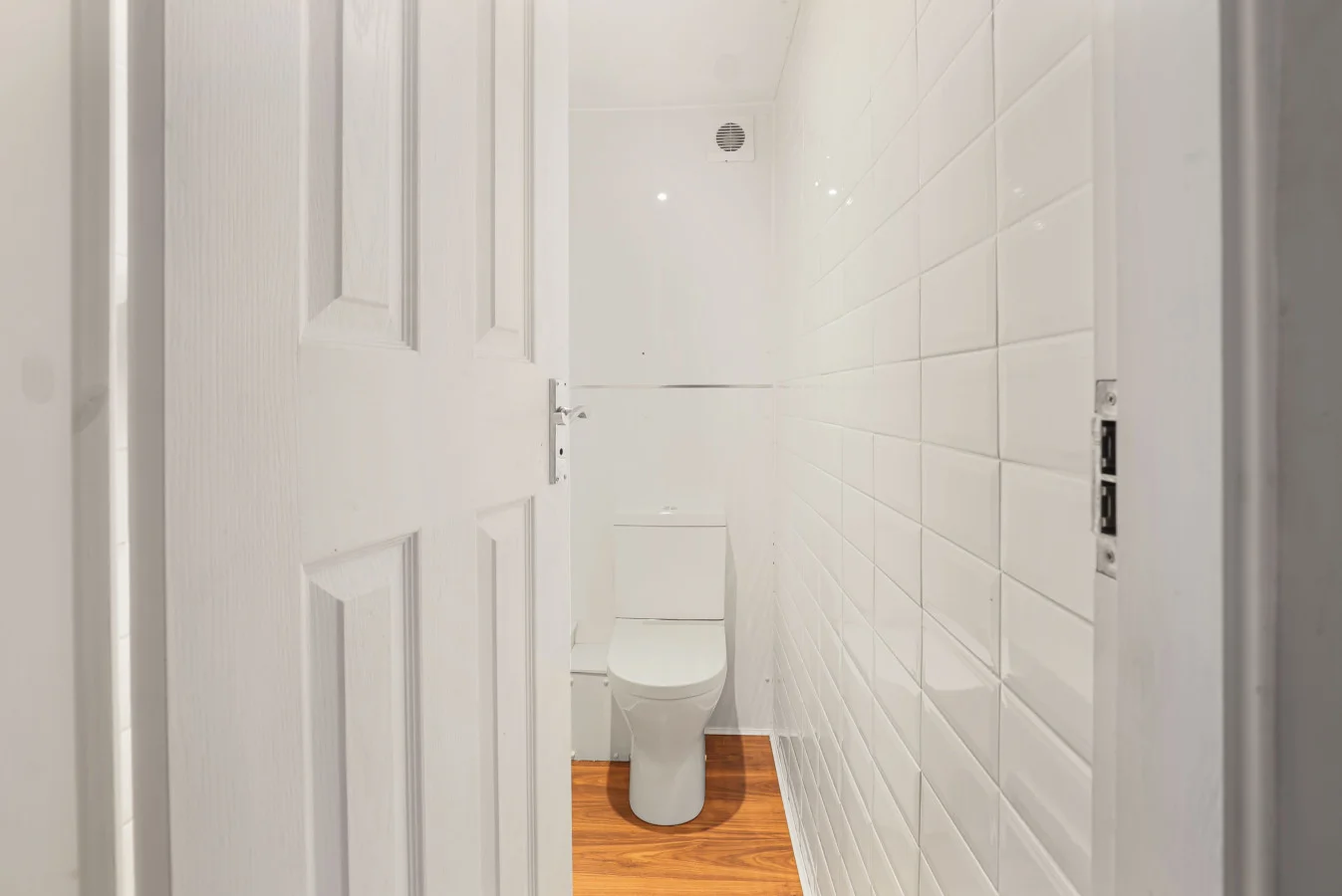 Ground-floor cloakroom with white tiled walls and timber flooring
