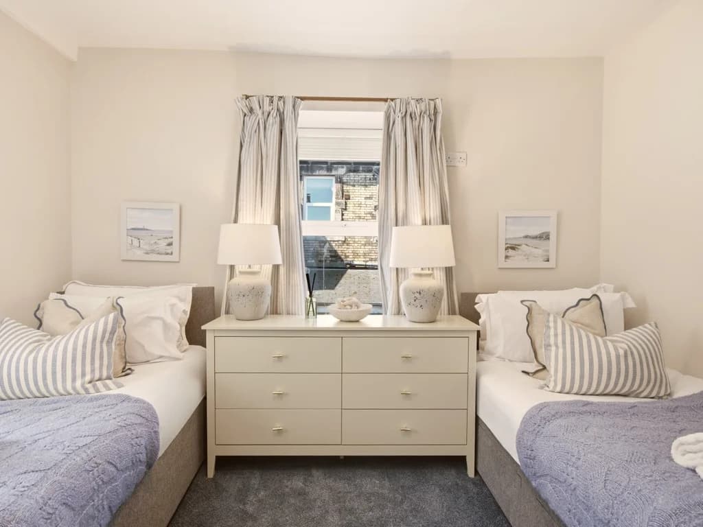 Twin bedroom with matching beds, bedside chest and soft neutral décor.