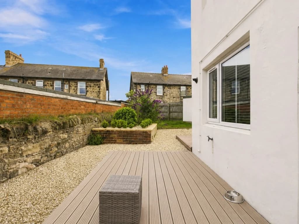 Enclosed rear garden with raised planting beds and decked seating area.
