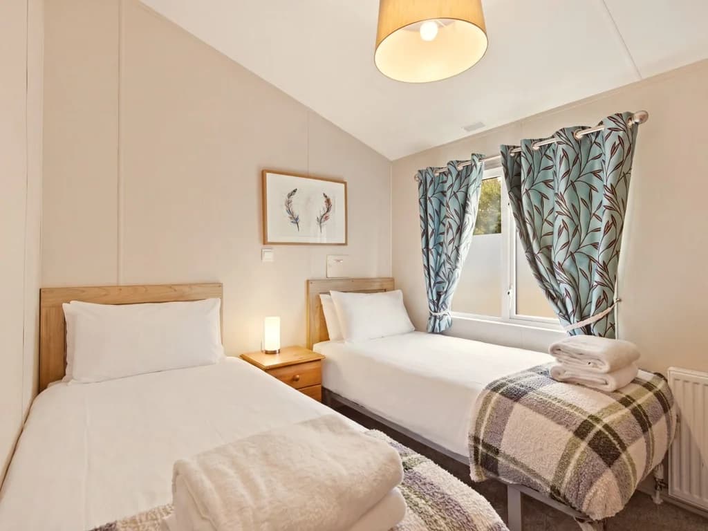 Twin bedroom with two single beds, bedside table and natural light