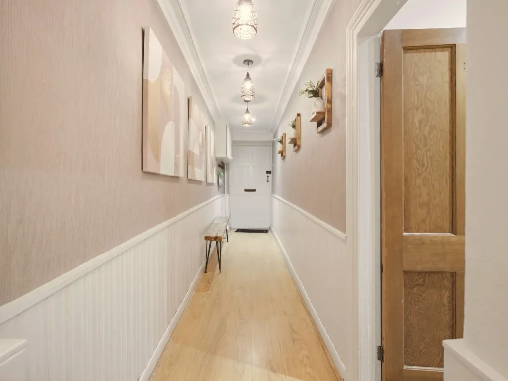 Long hallway with decorative lighting, wood flooring and wall artwork.