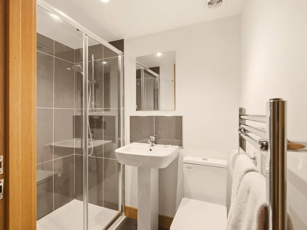 Private en-suite with glass shower, WC and pedestal wash basin