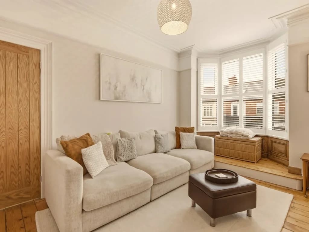 Comfortable living room with corner sofa, bay window and wooden flooring