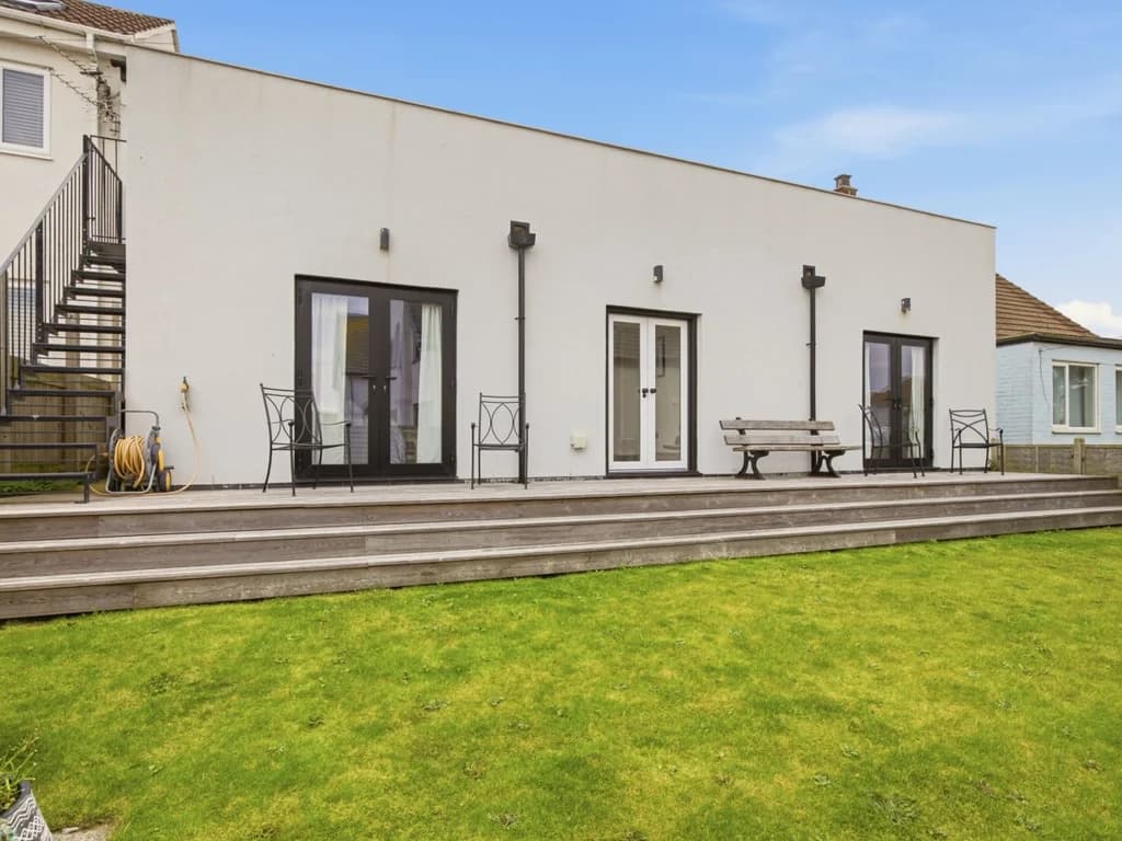 Rear garden with raised timber decking, outdoor seating and external staircase