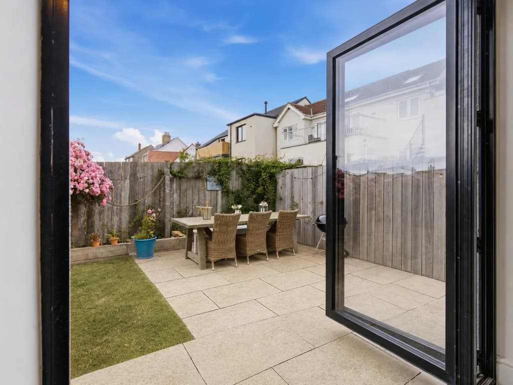 Patio with outdoor dining set, lawn and flowering shrub borders