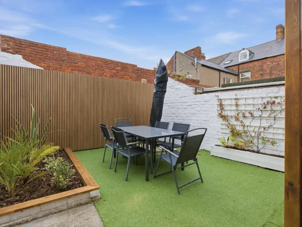 Enclosed outdoor dining area with seating, planting and privacy screening