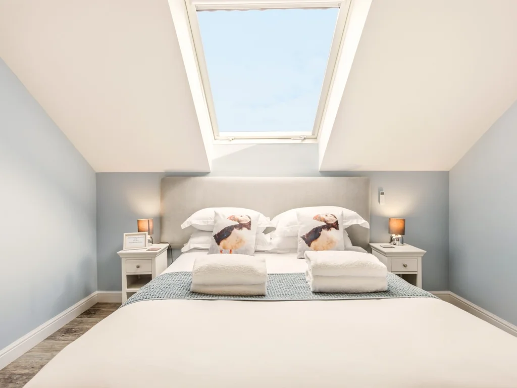 King-size bedroom beneath a skylight with bedside tables and lamps
