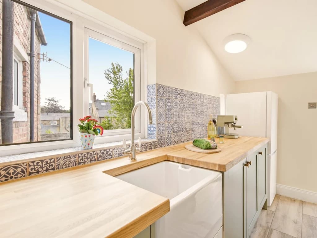 Butler sink beneath the window with patterned tiled splashback.
